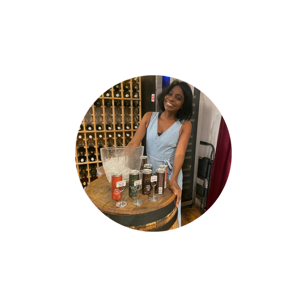 Woman standing behind a bar with various bottles and glasses.